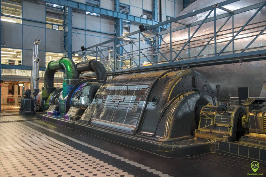 Industrialne wnętrze EC1 z zachowanymi, dawnymi maszynami i rurami przemysłowymi.
