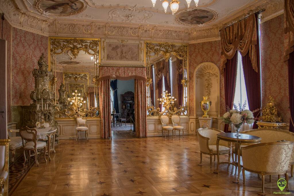Bogato zdobiony, zabytkowy salon w Pałacu Herbsta z meblami z epoki i kryształowym żyrandolem.