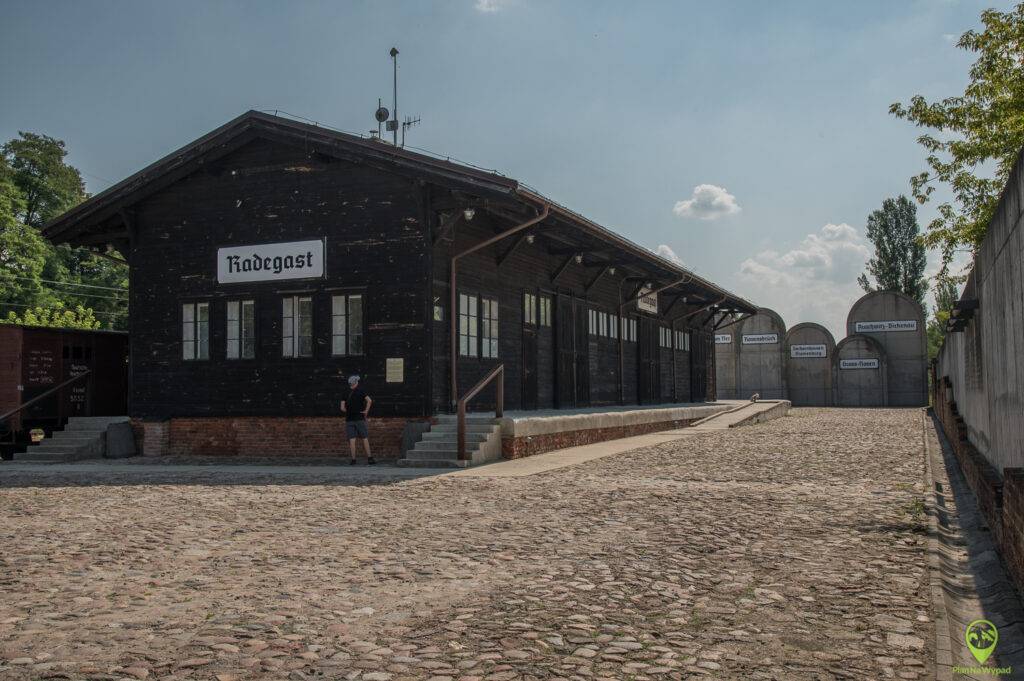 Zrewitalizowany drewniany budynek historycznego dworca Stacja Radegast z napisem stacyjnym.