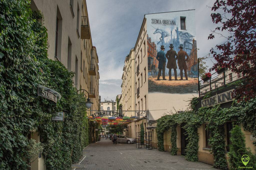 Mural Ziemia Obiecana Łódź na podwórku z parasolkami.
