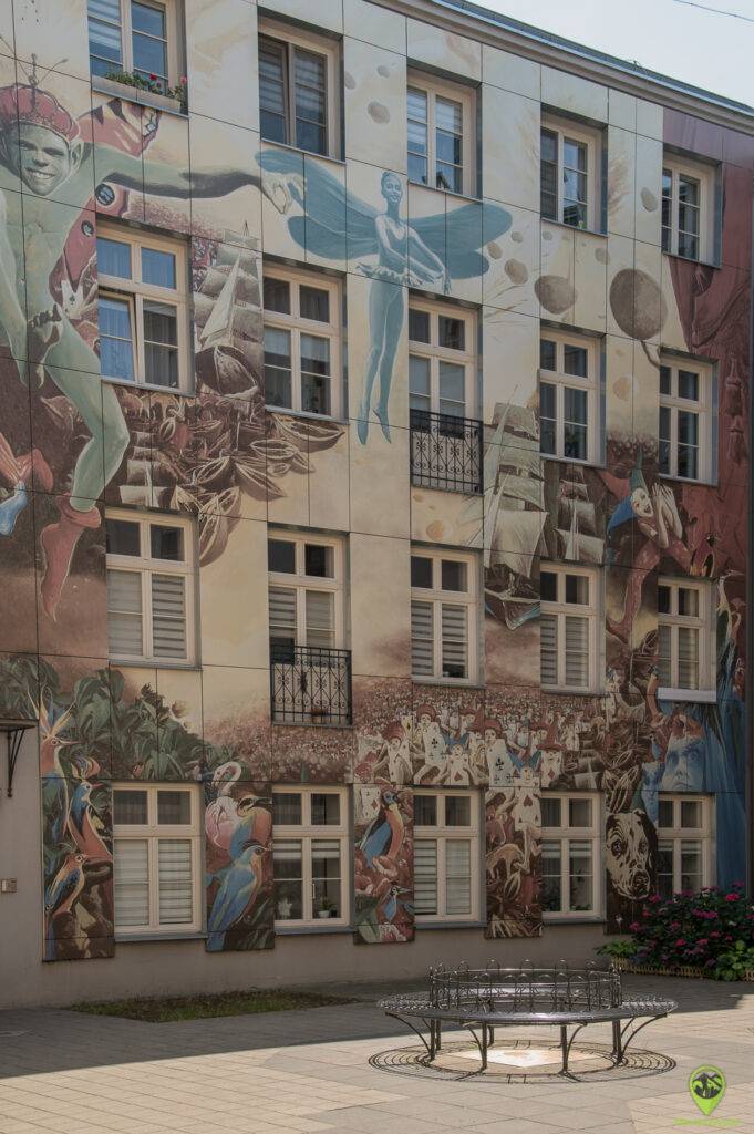 Geometryczny, nowoczesny street art pokrywający całą boczną elewację kilkupiętrowego budynku.